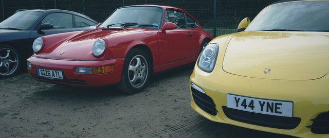 A red classic Porsche 911 beside a yellow Porsche convertible.