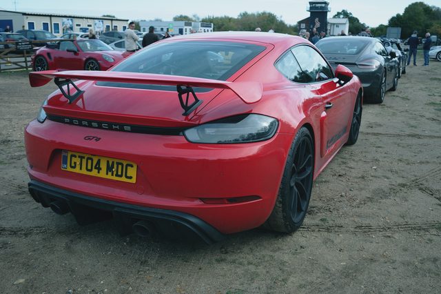 A red Porsche with a large rear wing, from behind.