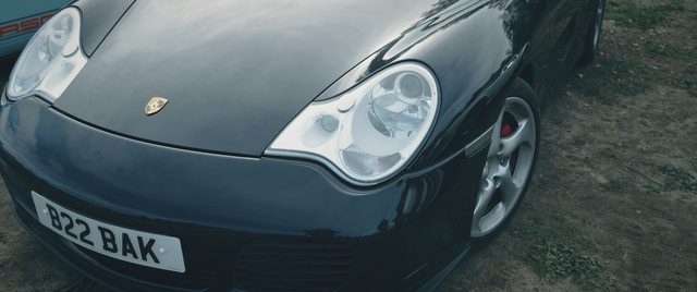 The bonnet and headlights of a black Porsche 911, close up.