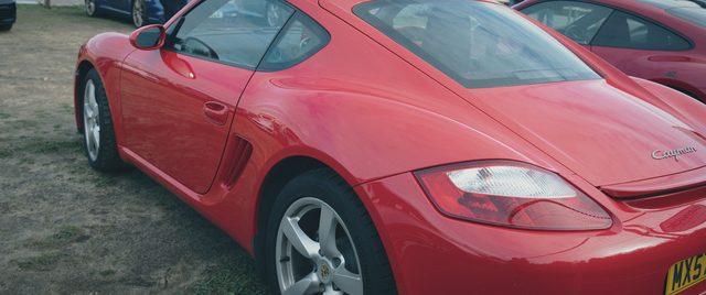 A red Porsche Cayman, close to the camera.