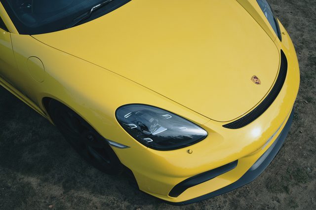 The headlamp and vent of a yellow Porsche, from above.