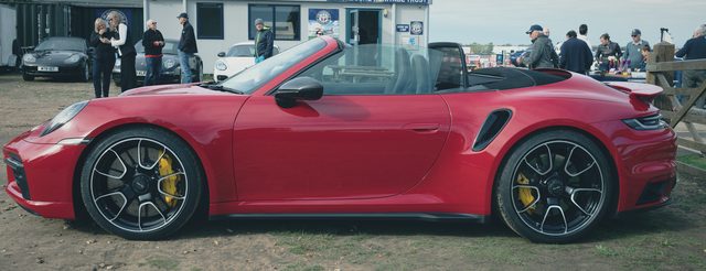 A red Porsche 911 convertible with yellow brake calipers, side on.
