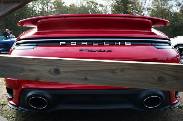 The rear of a red Porsche 911 Turbo S, its PORSCHE lettering above a wooden rail.