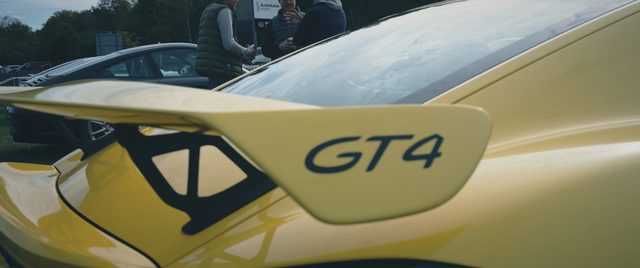 The rear wing of a yellow Porsche GT4, close up.