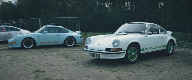 The white classic 911 parked beside the pale blue 911.