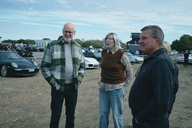 Three owners talking and laughing between the parked cars.