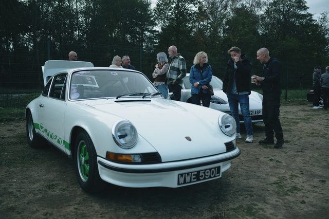 The white classic 911 head-on, owners talking around it.