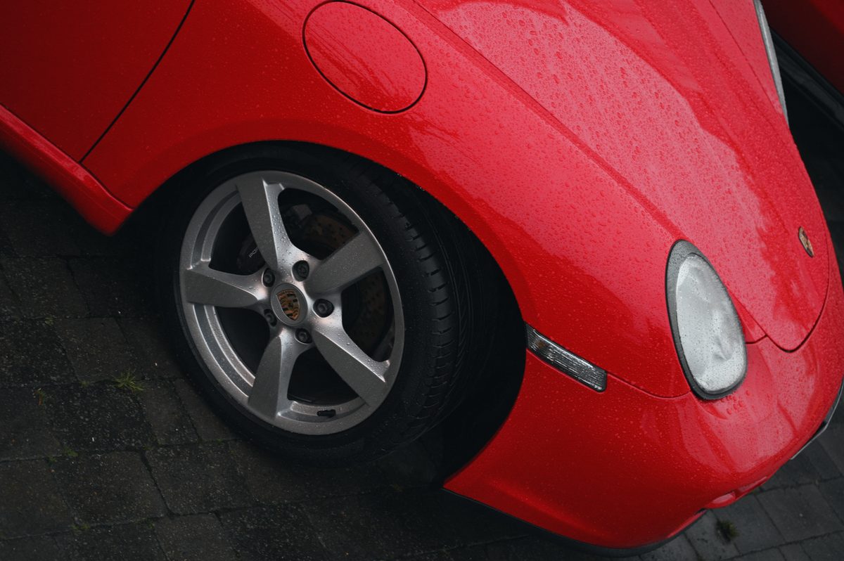 Rain on the red front wing and the wheel of a Porsche Cayman.
