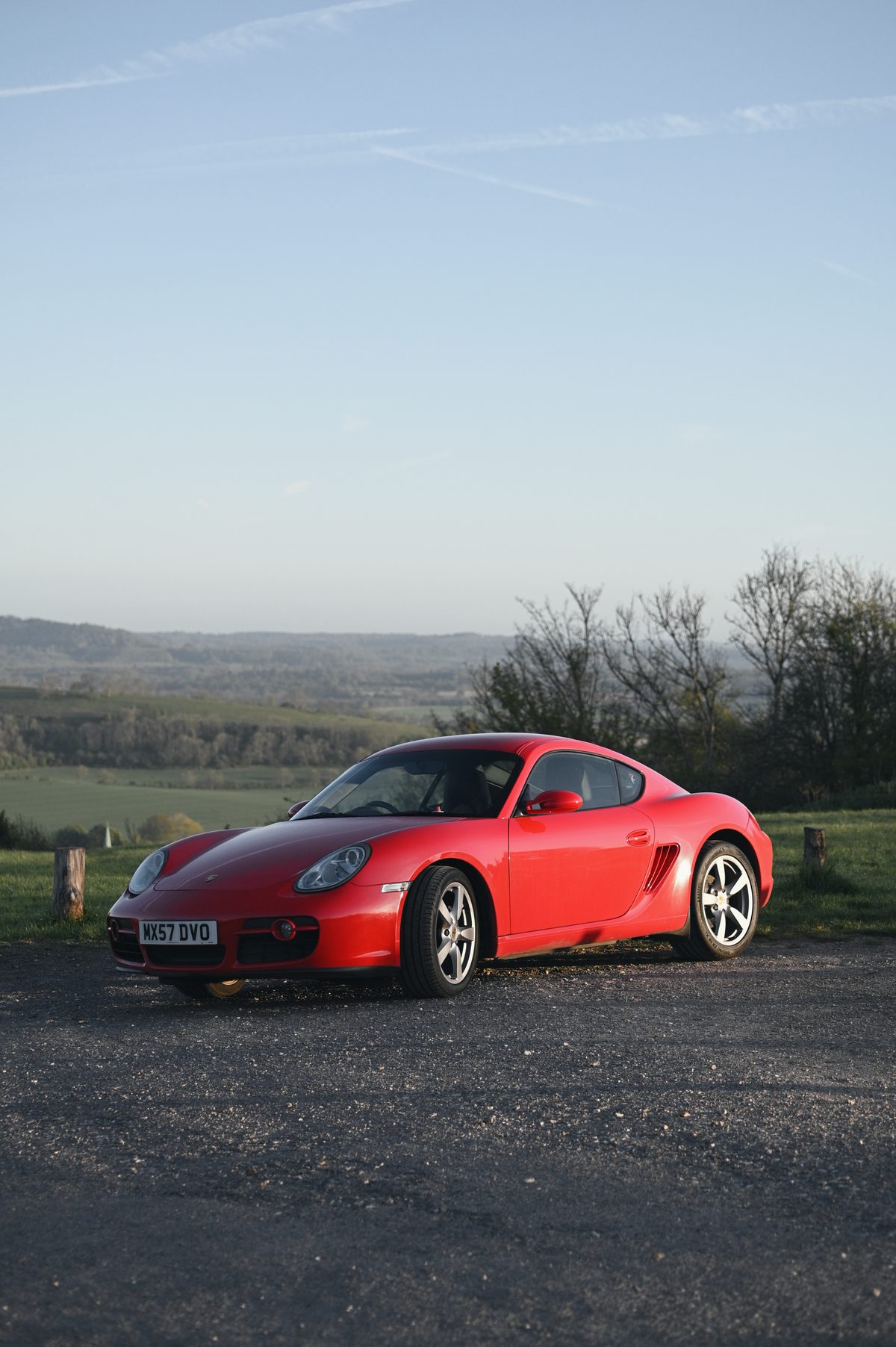 A small red Cayman under a wide blue sky.