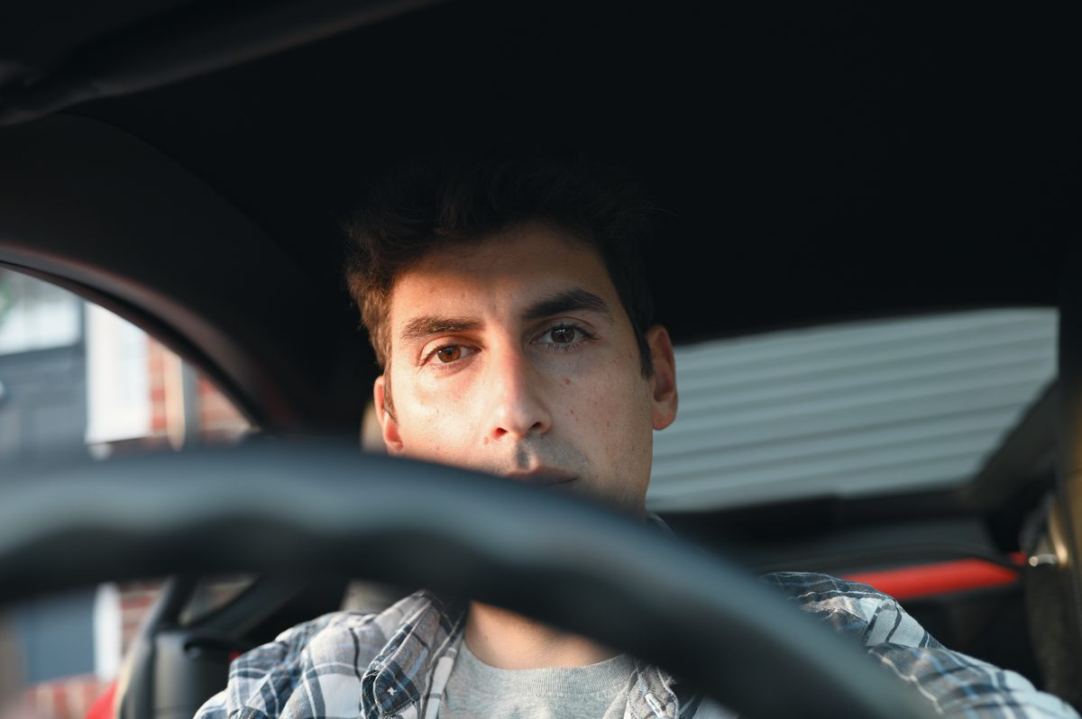 David looks straight at the camera over the steering wheel.