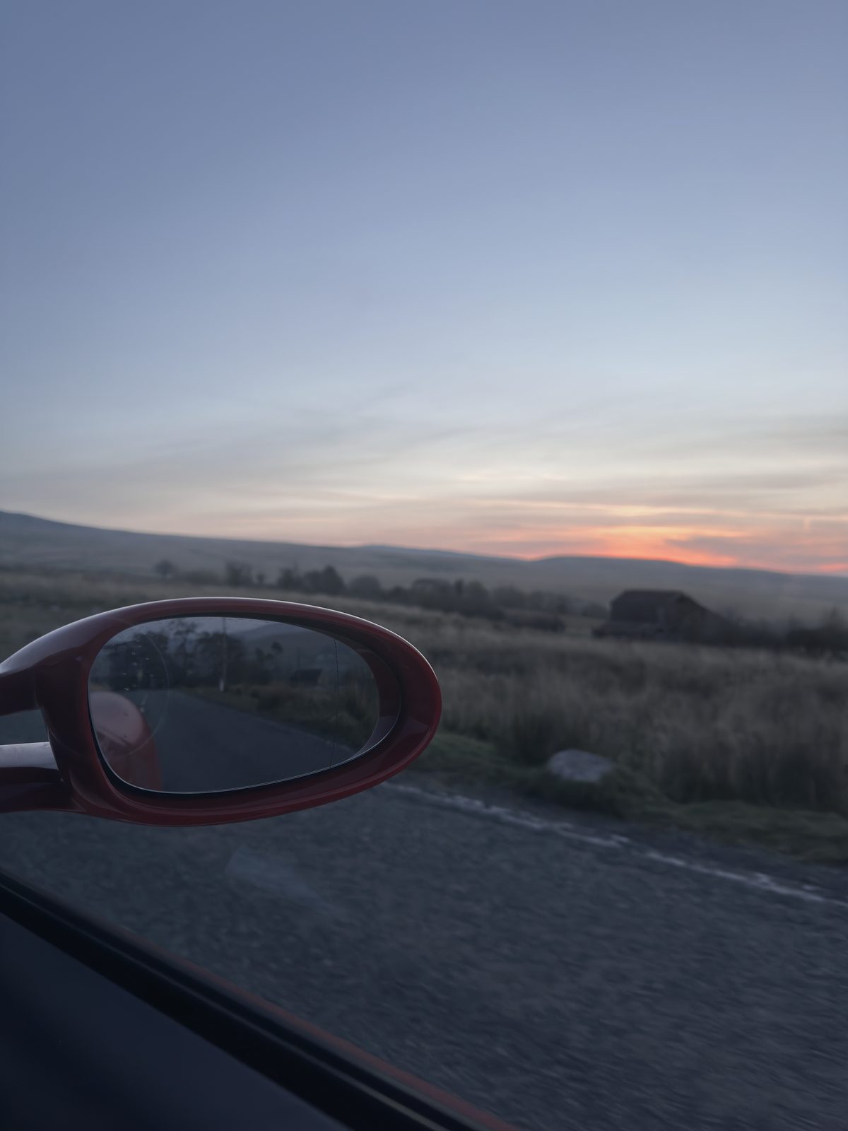 The red door mirror, an orange line of light on the horizon.