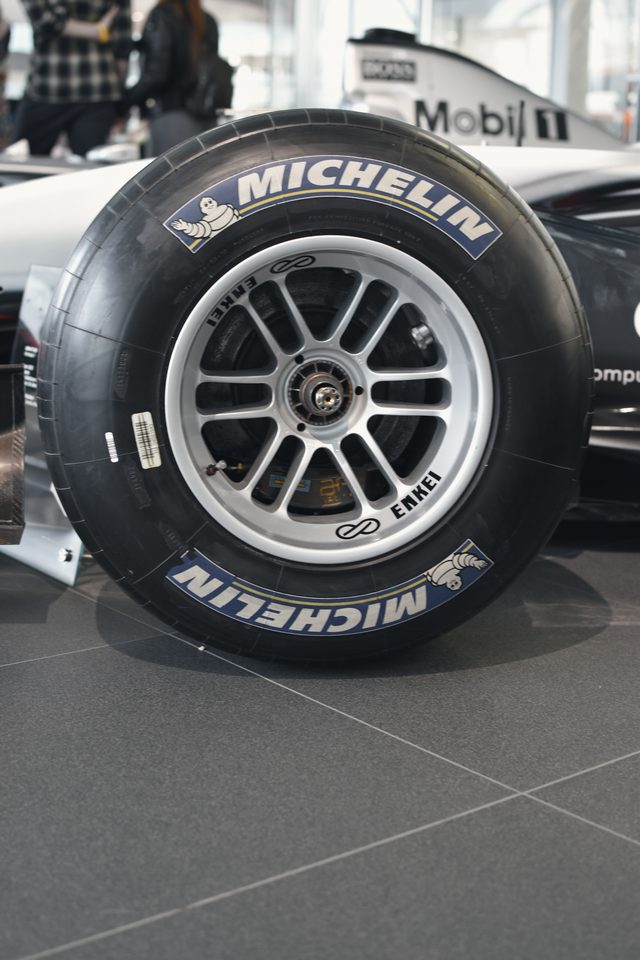 A Michelin racing tyre and silver wheel on a grey and black car.