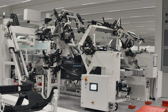 Robot arms and white machines on the assembly line.