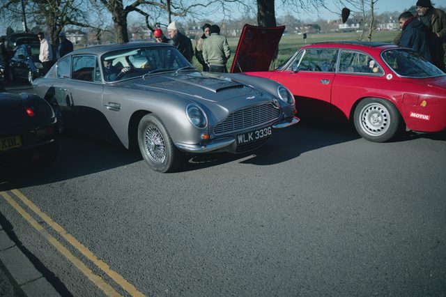 A silver grand tourer and a red coupé side by side in low winter sun.