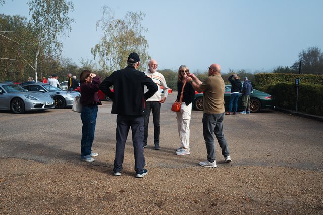 A small group still talking in a gravel car park as the meet winds down.