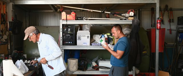 Two men in the shed, reading the labels on bottles and cans.